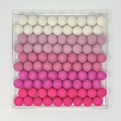 there are many balls in the box on the table and one is pink, white, and purple