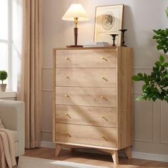 a room with a white couch and a wooden dresser next to a lamp on a table