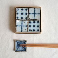 chopsticks are laying next to a blue and white box with squares on it