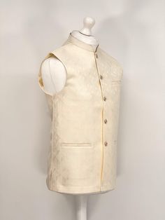 Introducing our exquisite Men's Jamawar Waistcoat, a luxurious addition to any gentleman's wardrobe. Handcrafted from the finest quality Jamawar fabric, this waistcoat is fully lined for added comfort. Featuring a timeless design, it comes with Gold buttons that add a touch of elegance to any outfit. The waistcoat also comes with pockets, providing ample storage space for your essentials. Perfect for formal occasions, this waistcoat is sure to make a statement and impress all those around you. Formal Beige Vest Outerwear, Classic Nehru Jacket With Stand Collar For Wedding, Classic Beige Nehru Jacket For Formal Occasions, Cream Fitted Nehru Jacket For Semi-formal Occasions, Semi-formal Classic Nehru Jacket With Stand Collar, Classic Nehru Jacket For Business, Classic Tailored Nehru Jacket With Collar, Classic Nehru Jacket With Stand Collar For Business, Classic Cream Nehru Jacket For Formal Occasions