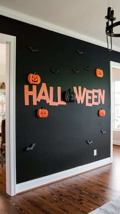 a black wall with halloween decorations on it and the word halloween spelled out in orange