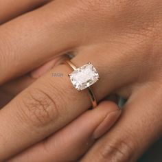 a woman's hand with a diamond ring on her left hand and the other hand holding an engagement ring