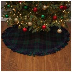 a christmas tree with ornaments on it and a green plaid rug underneath the tree skirt