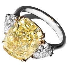 This exquisite ring features a GIA-certified 5.24-carat fancy yellow cushion-cut diamond, elegantly set in 18K white gold, with the upper portion supporting the central stone crafted in 18K yellow gold. The vibrant fancy yellow diamond captivates with its rich color, enhanced by the warm tones of the yellow gold setting.Accompanying the centerpiece are two pear-cut diamonds that add an element of sophistication and brilliance. The diamond's VVS2 clarity grade ensures it is nearly flawless, with Luxury Yellow Gold White Topaz Ring, Luxury Yellow Gold Diamond Ring In Recycled Gold, Luxury Gold Multi-stone Diamond Ring, Yellow Cushion, Elongated Cushion Cut, Cushion Cut Diamond Ring, Elongated Cushion, Yellow Cushions, Future Engagement Rings