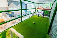 an indoor play area with artificial grass and soccer balls on the ground in front of it