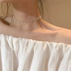 a woman wearing a white shirt with a silver choker on her neck and the word love spelled in cursive letters