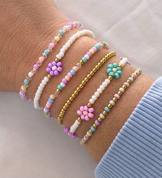 a woman's arm with four bracelets on it, one has flowers and the other has beads