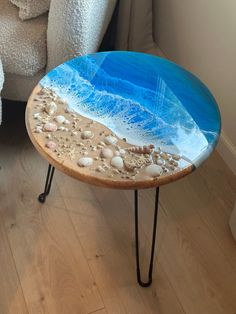 a table with shells and sand on it sitting in front of a couch next to a chair