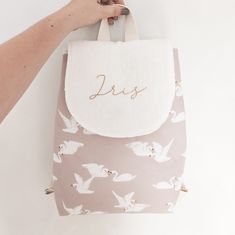 a hand holding a bag with swans on it and the word jesus written in gold