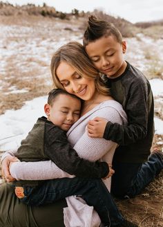 a mother hugging her son while he sits on the ground with his arms around him