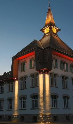 an old building with a clock tower lit up at the top and windows on each side