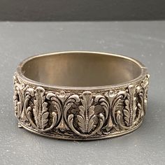 WIDE ~ Vintage Victorian revival ~ Heavily silver plated ~ hinged bangle /bracelet with applied /raised scroll design on top and embossed body ~ Bangle has a hidden tongue and box clasp with double safety chain . Dates 1950's ~ Unsigned Material : silver plated metal Dimensions : Bangle is 7 1/4 inches in total length x max width of 1 inches in center . Condition :- Overall good vintage condition ~ Some metal discoloration /darkening seen ~ Very less wear /loss to silver plating ~ Clasp is in go Victorian Revival, Filigree Jewelry, Victorian Gold, Safety Chain, Box Clasp, Hinged Bracelet, Scroll Design, Vintage Victorian, Hinged Bangle