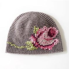 a gray knitted hat with pink flowers on it