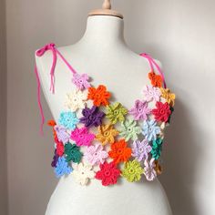 a white mannequin with multicolored crocheted flowers on it's chest