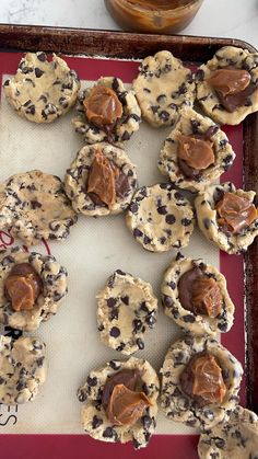 cookies with peanut butter and chocolate chips on a baking sheet next to a glass jar