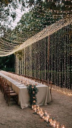 a long table is set up with candles and greenery for an outdoor wedding reception