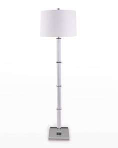 a floor lamp with a white shade on it's base and a silver metal base