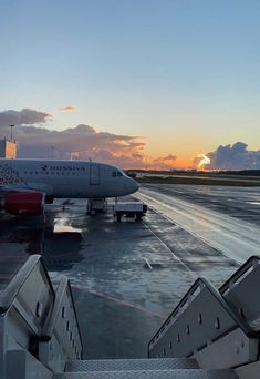 an airplane is parked on the tarmac at sunset