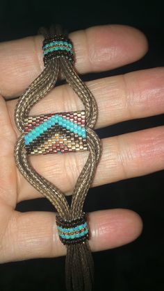 a hand holding a brown and blue beaded bracelet on it's palm,