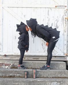 two women in black hoodies and leggings are standing on steps with their heads together