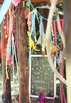 a chalkboard sign is covered with streamers and confetti hanging from it