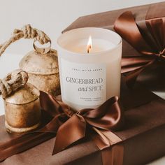 a candle sitting on top of a wrapped present box next to a tea kettle and bow