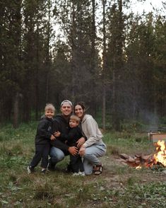 a family sitting in front of a campfire with the fire lit up behind them