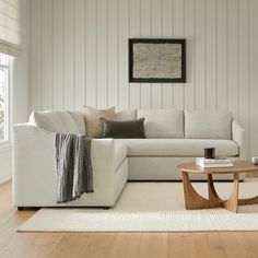 a living room with white walls and wood flooring is pictured in this image, the couch has two pillows on it