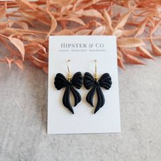 These black bow dangle earrings are super lightweight and a great statement accessory. These earrings are handmade out of black polymer clay in small batches. Dimensions: Length: approximately 2 inch Width (at widest point): approximately 1 inch Materials Polymer clay Gold-finished stainless steel fish hook Resin PLEASE NOTE Each earring is handmade and so dimensions may differ slightly. Colors may differ based on computer settings. Super Clay Earrings, Bow Clay Earrings, Polymer Clay Hair Accessories, Bow Clay, Air Dry Clay Jewelry, Fondant Seashells, Polymer Clay Designs, Clay Earrings Black, Black Polymer Clay