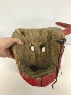 someone is holding up a mask made out of wood with horns and holes in it