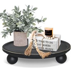 a black tray with a plant, candle and some books sitting on top of it