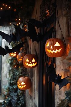 pumpkins and bats are hanging from the side of a building with lights on them