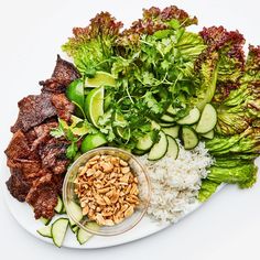 a white plate topped with meat and veggies next to rice covered in sauce