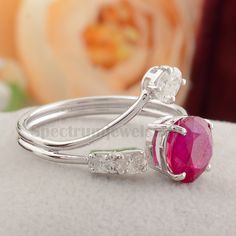 a close up view of a ring with a pink stone in the middle and two white diamonds on each side