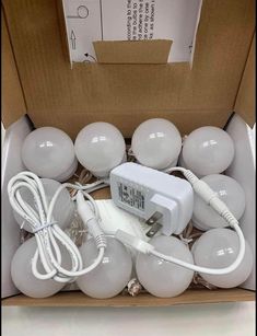 an open box filled with white light bulbs and plugged into the wall charger