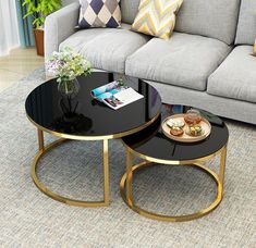 two tables sitting on top of a carpeted floor in front of a gray couch