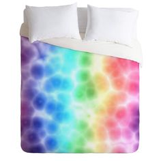 a bed with a rainbow colored comforter and pillows