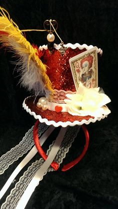 a red and white hat with some feathers on it's headband, sitting on a black surface