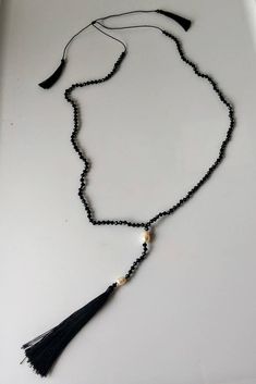 a long black beaded necklace with a tassel