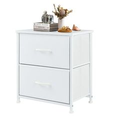 a white cabinet with two drawers next to a potted plant and books on top