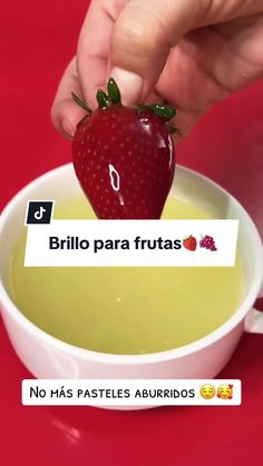 a person holding a strawberry over a bowl of soup with the words brillo para frutas on it