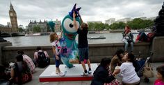 children are sitting on steps near a statue of a cartoon character in london, england