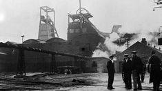 black and white photograph of men standing in front of an old factory