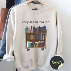 there is a white sweatshirt with books on it and the words, they see me rollin '