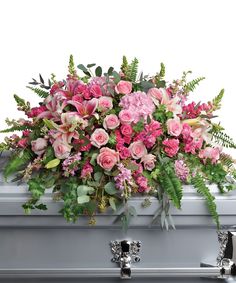 a casket filled with pink flowers and greenery