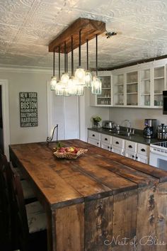 a kitchen with an island made out of wood and lights hanging from it's ceiling