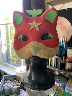 a red cat mask sitting on top of a black mannequin head