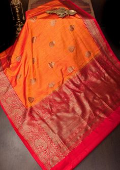 Dupion Silk is a unique kind of silk known for its matt texture. The use of antique gold tone zari gives it a regal look. The saree is sought after for its rustic charm and never fails to make a statement.  This pure Dupion Silk Saree comes in a combination of mustard and orange stripes wirh red borders. It features antique zari damask zari buttas and beldar vine borders.  SILK MARK CERTIFIED This saree is ready to wear with fall and pico done. Handmade silk tassels adorn the pallu and add more Dupion Silk Saree, Orange Saree, Silk Tassels, Banarasi Silk Saree, Dupion Silk, Blouse Fabric, Saree Wedding, Rustic Charm, Silk Saree