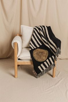 a black and white blanket sitting on top of a wooden chair next to a wall