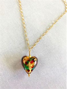 "Sweet, Heart pendant necklace of genuine Murano glass from the artisans in Murano, Italy! You will love this pretty glass pendant that is full of color and whimsy. Show her that you love her with this heart of multi colors swirling and dancing. The glass has 14k gold foil within them to add to the sparkle of colors of gold, red and green ! The gorgeous chain is Gold Fill with lobster claw clasp. The glass heart bead is about 3/4 of an inch and then the drop of the total pendant is about 1.25 in Czech Glass Round Pendant Necklace For Gifts, Czech Glass Round Pendant Necklace As Gift, Czech Glass Round Pendant Necklaces As Gifts, Czech Glass Round Pendant Necklaces For Gifts, Valentine's Day Glass Necklaces Gift, Glass Heart Pendant Necklace For Gift, Elegant Glass Heart Pendant Necklaces, Heart-shaped Glass Necklace For Valentine's Day, Valentine's Day Heart-shaped Glass Necklace